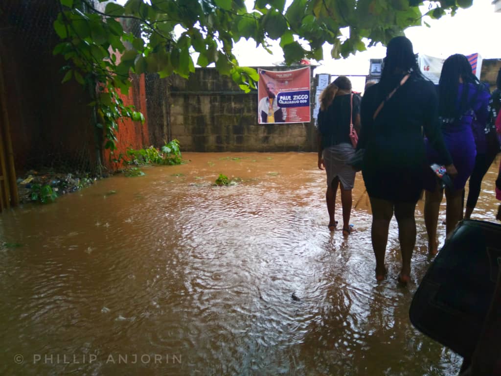 Students trying to leave through the gate amid rainfall.